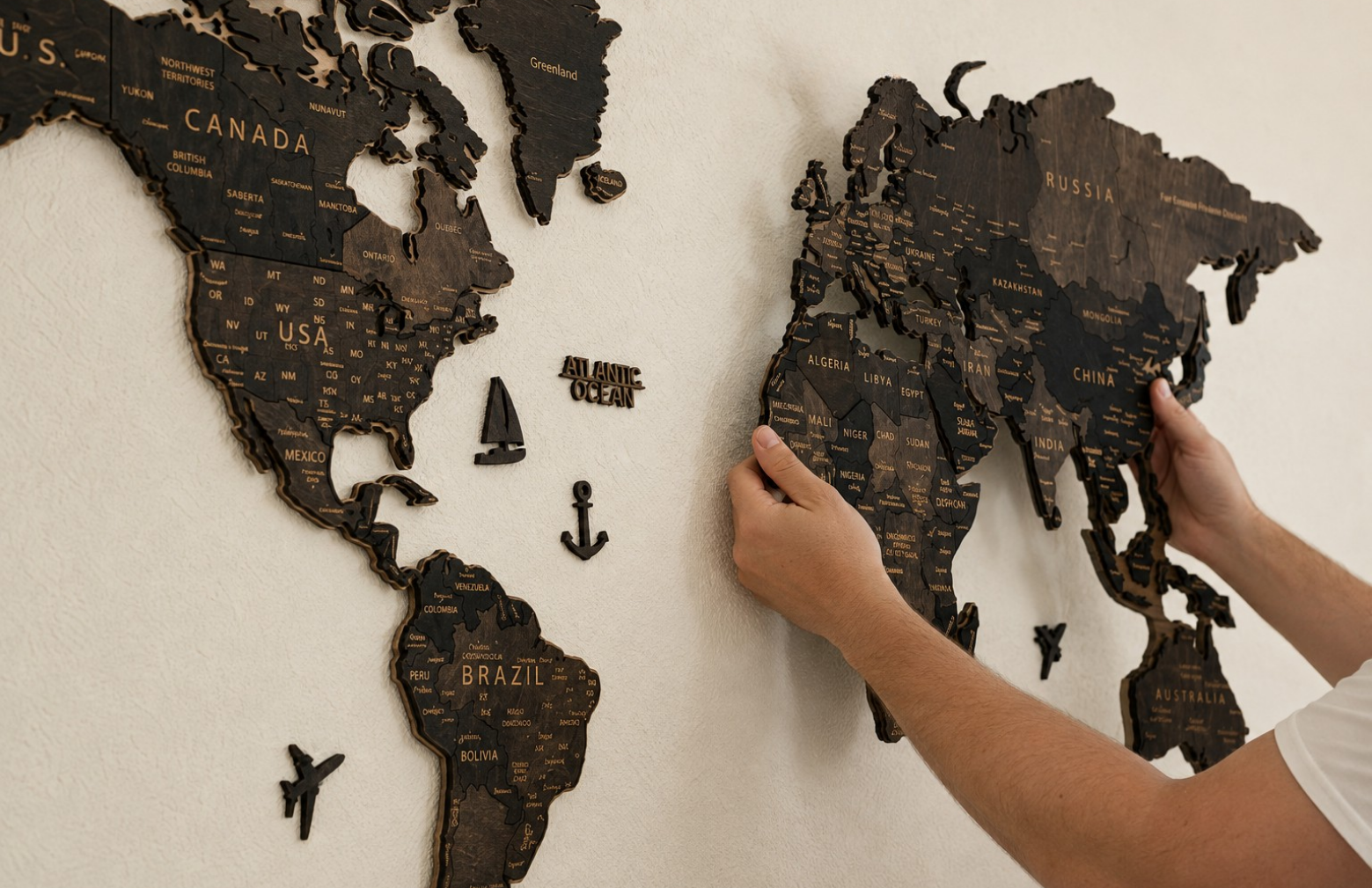 Person installing the main elements of a Pinelini 3D wooden world map on a wall