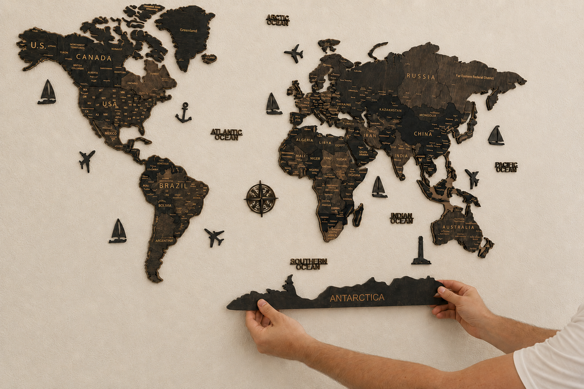 Person adding the separate Antarctica element to a Pinelini 3D wooden world map
